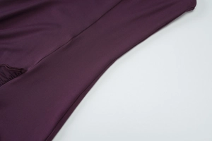 Detail of deep purple dress fabric showing soft texture and elegant ruffled stitching line