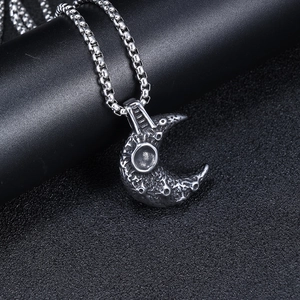 Macro shot of silver moon pendant with realistic crater texture on stainless steel chain