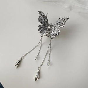 Detailed macro view of silver butterfly hair clip with sparkling rhinestones and metal tassels