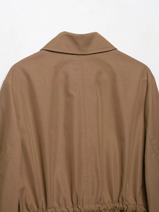 Detail view of brown lapel jacket featuring twill texture and cinched waist stitching