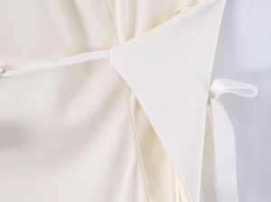 Detailed close-up of bow tie knot and premium stitching on ivory halter top