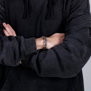 Close-up of vintage silver dragon-patterned chain bracelet worn on a wrist