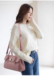 Detailed shot of pink crocodile pattern handbag with woven handles and metal twist lock