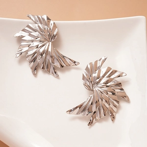 Detail view of large silver polished spiral leaf earrings on a white ceramic plate