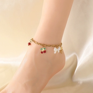 Détail d'une chevillère dorée avec pendentifs cerise, nœud et tournesol portés à la cheville