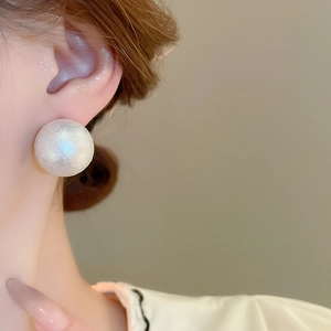 Primo piano di un grande orecchino a perla bianco caldo indossato con stile elegante