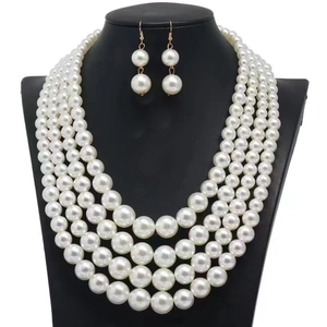Detailed view of the four-layer pearl necklace and matching earrings on a black bust