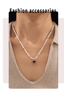 Detail of red heart zircon pendant on pearl necklace worn by a fashion model