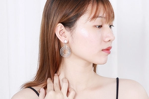Detail of silver triple-layered circular geometric drop earrings worn by a model