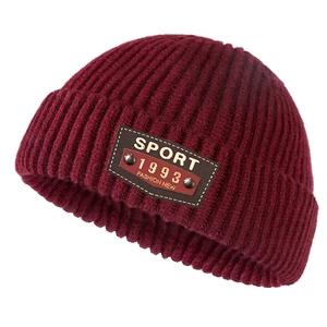 Burgundy knitted beanie with thick ribbed texture and vintage leather sport patch