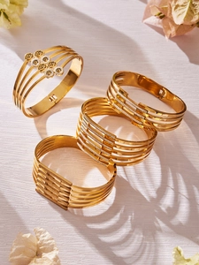 Dettaglio di quattro bracciali in acciaio inossidabile dorato con albero della vita e design