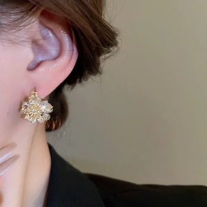 Close-up of elegant gold flower earrings with crystals on a model for a luxury style
