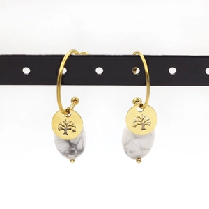 Detail of tree of life earrings with white marble teardrop charms on a display stand