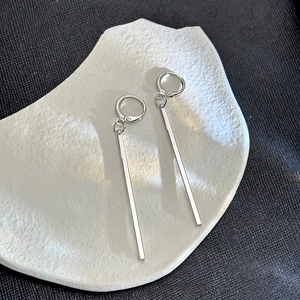 Detail shot of silver long geometric drop earrings on a white stone tray backdrop