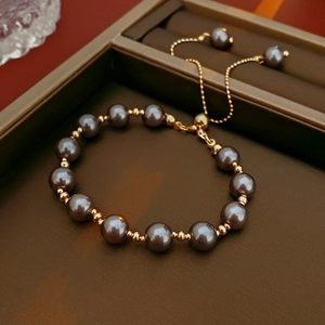 Detail of dark gray pearl bracelet with gold beads and adjustable drawstring clasp