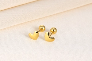 Macro view of gold heart screw back earrings on soft beige silk background