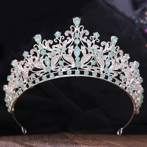 Close-up of luxury bridal crown with green crystals and rhinestones on black background