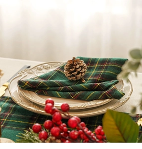 Close-up of green plaid Christmas napkin on beige relief plate with pine cone decoration