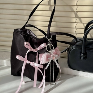 Black satin ballet style handbag with pink bows and lace metal pendant under natural light