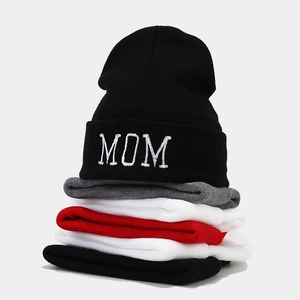 Stacked display of knitted beanies in various colors with white MOM embroidery