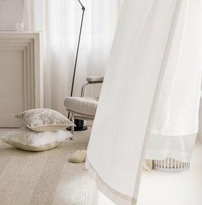 Detail of stacked beige patterned and white plush sofa cushions on a woven rug