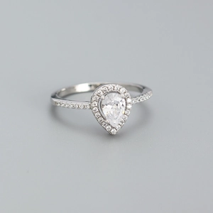 Macro shot of silver ring with pear-cut halo diamond and sparkling pavé band detail
