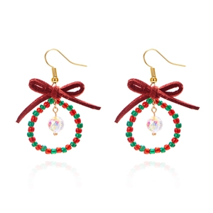 Macro detail of Christmas wreath earrings with red bow and faceted crystal drop