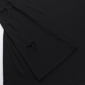 Dettaglio del design a cuore traforato sul polsino in maglia a coste nera di classe