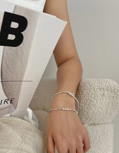 Close-up of S925 sterling silver knotted bangle and delicate pearl bead bracelet set