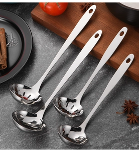 Close-up of four thick stainless steel long-handle ladles and skimmers on kitchen counter