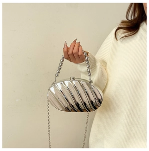 Detail of silver shell-shaped acrylic evening bag with wave texture and bead handle