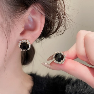 Macro view of French retro round earrings with black gemstone and gold crystal halo