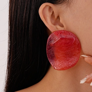 Close-up of a vibrant red resin irregular earring with brushed texture on model
