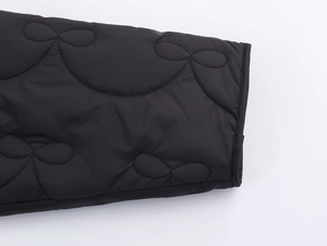Gros plan détaillé du poignet d'une veste matelassée noire avec motif de nœud surpiqué