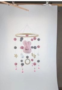 Detail of hanging baby mobile with plush pink bunny, wooden star and colorful felt balls