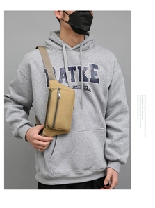 Detail view of khaki canvas waist bag on a model showing double zipper pockets and strap