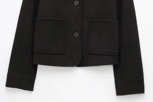 Detail of soft black jacket featuring functional chest pockets and buttoned cuffs