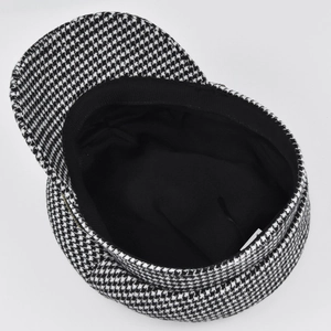 Detail of black and white houndstooth baker boy hat featuring woven texture and inner lining