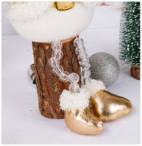 Détail de bottes dorées de poupée de Noël avec jambes perlées sur une bûche en bois