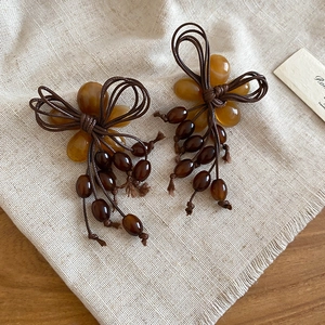 Detail of handmade resin bow earrings with dark brown beads tassels in retro style
