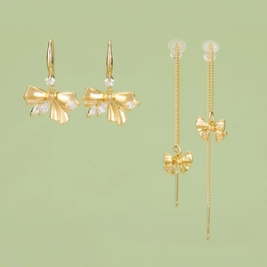 18k gold plated bow pendant earrings with cubic zirconia charms on green background