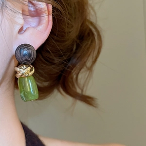 Gros plan sur des boucles d'oreilles géométriques en résine et anneau tressé