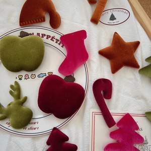 Flat lay of velvet Christmas ornaments like stars and stockings on white fabric