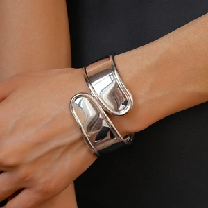 Close-up of minimalist silver wide wrap bracelet with polished irregular open loop design