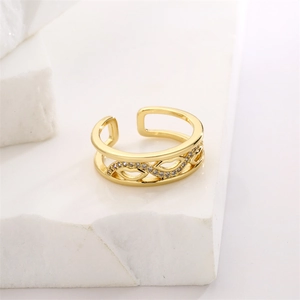 Detail of golden wavy ring with zircon stones on white stone surface