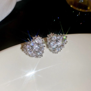 Macro shot of silver heart stud earrings with sparkling cubic zirconia on white surface