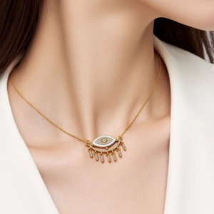Close-up of a gold-plated evil eye necklace with white enamel and sparkling zircon tassels