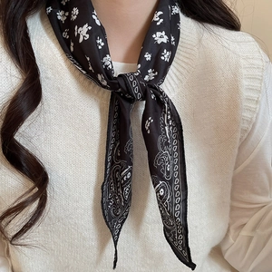 Close-up of a black silk scarf necklace with white floral and paisley patterns