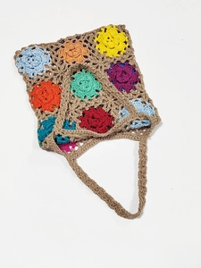 Detailed close-up of colorful handmade crochet flowers on a brown woven handbag