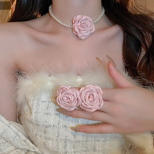 Ensemble collier en perles et bague camélia rose en tissu sur un modèle élégant